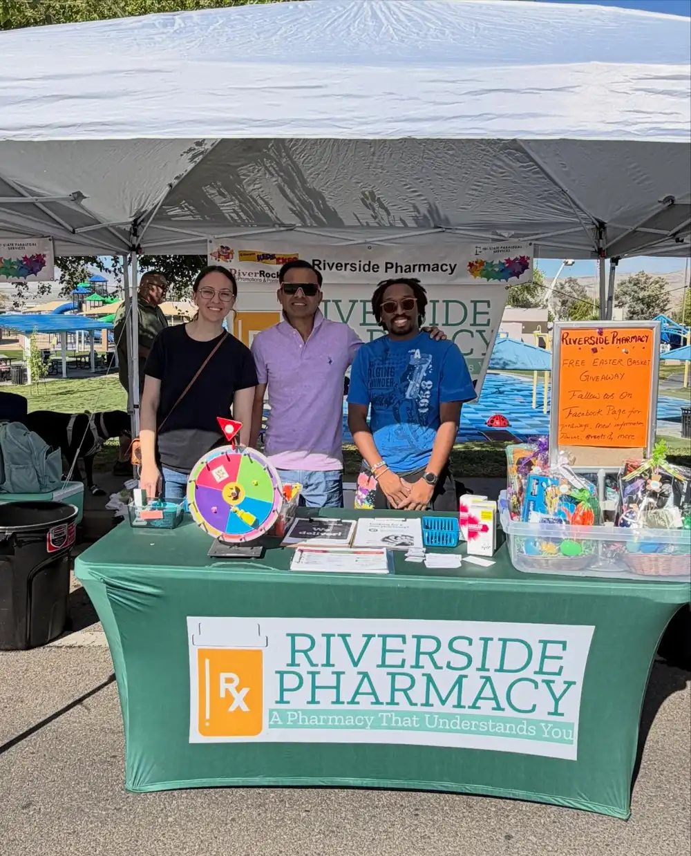 Riverside Pharmacy staff at a community event booth with a prize wheel