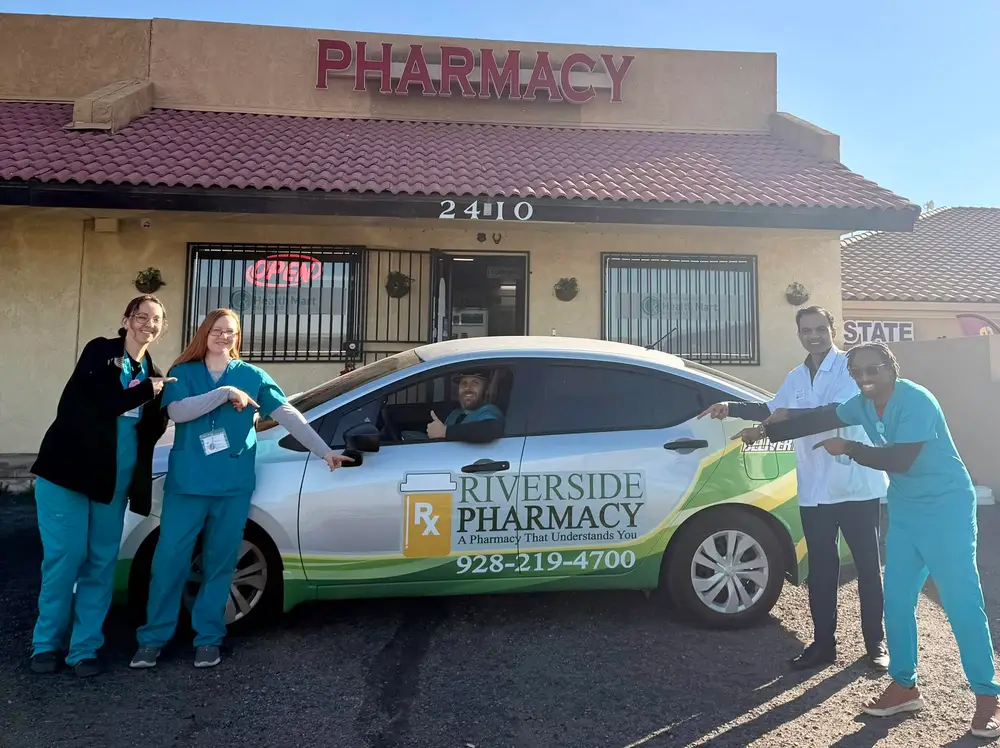 Staff pointing at the Riverside Pharmacy delivery car outside the Highway 95 storefront